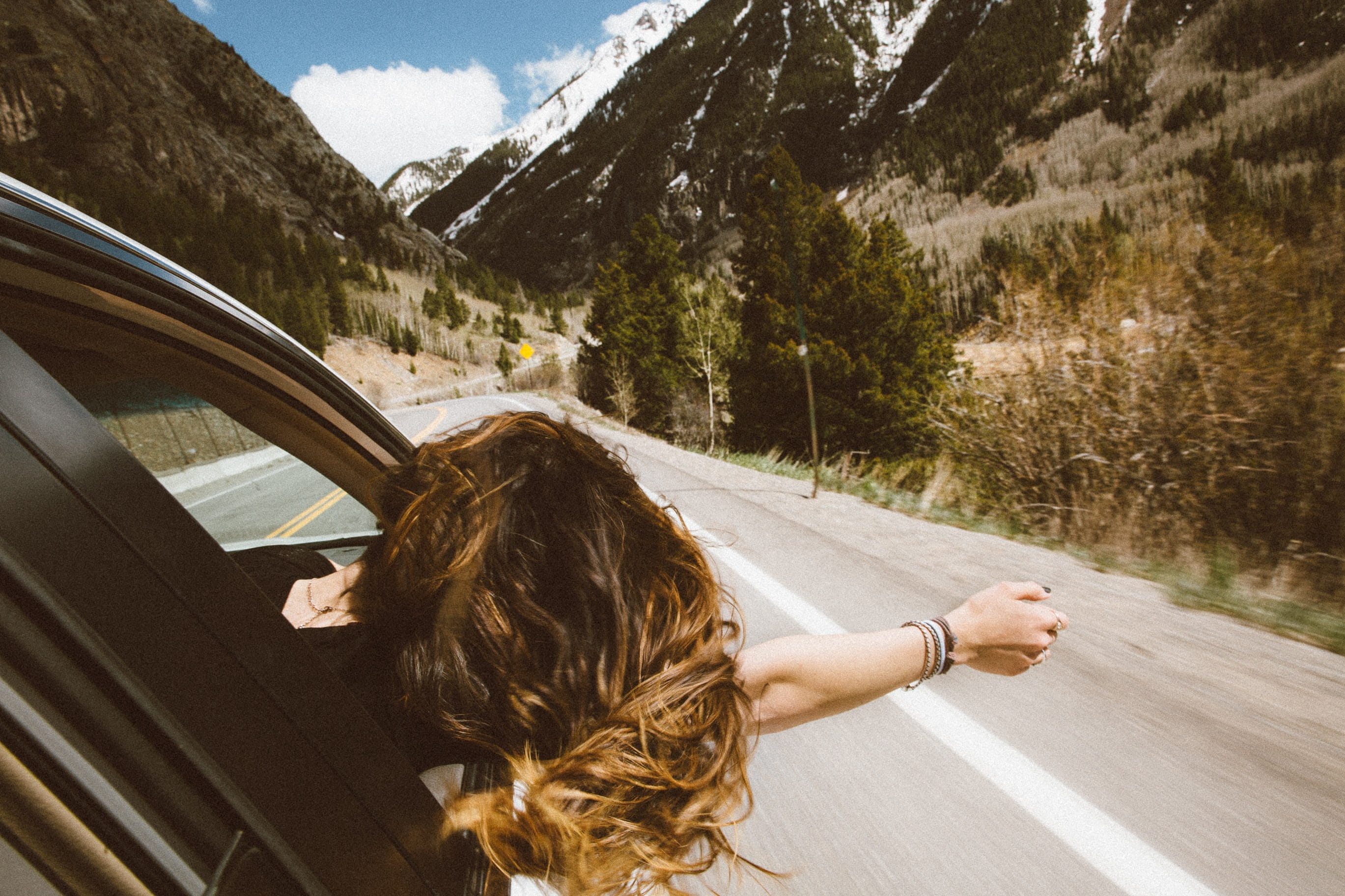 woman hanging arm out car window